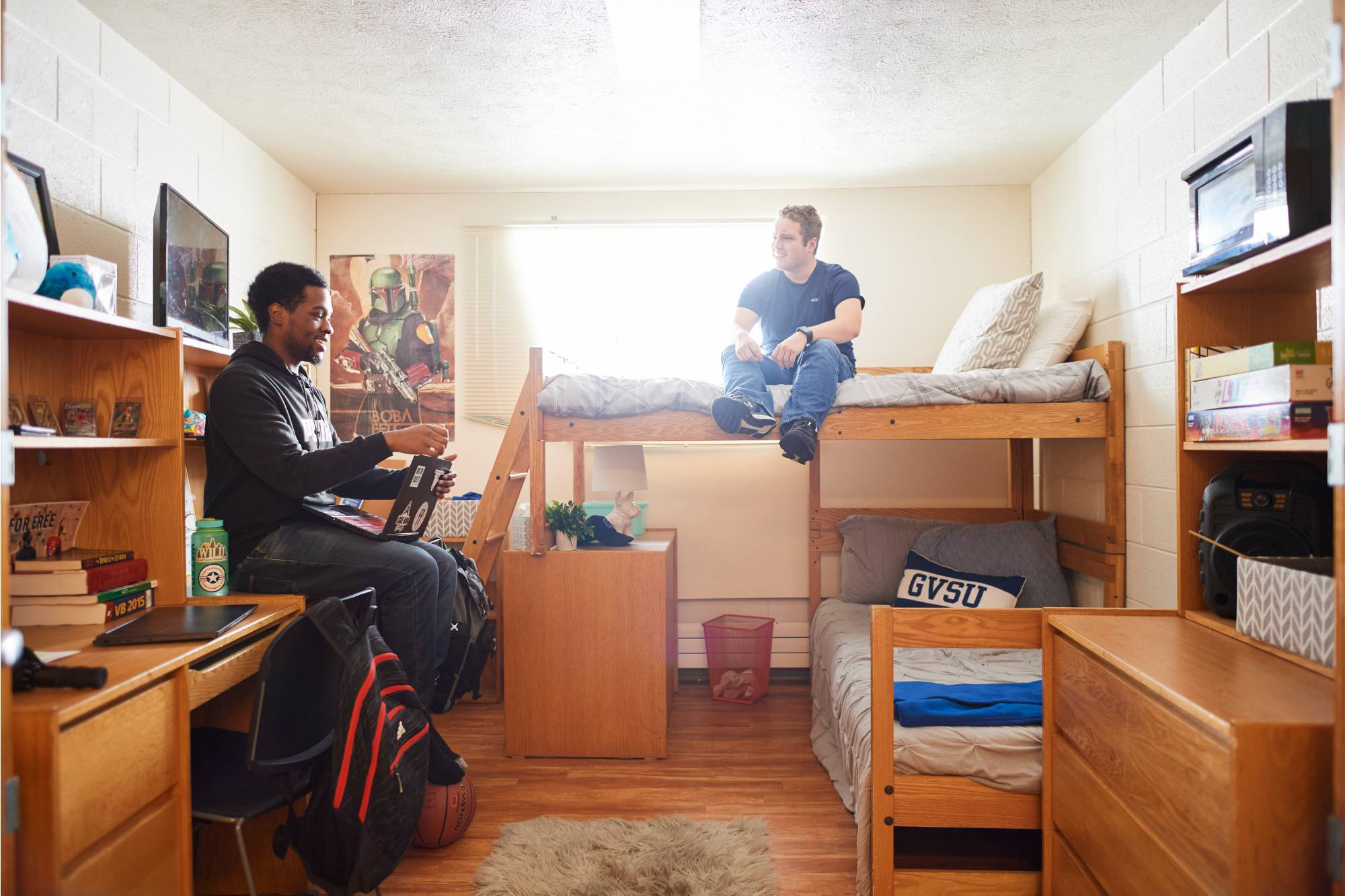 Two young men in a Copeland room. One sits at a desk with a laptop, the other on a lofted bed. The room is tidy and bright, conveying a relaxed atmosphere.
